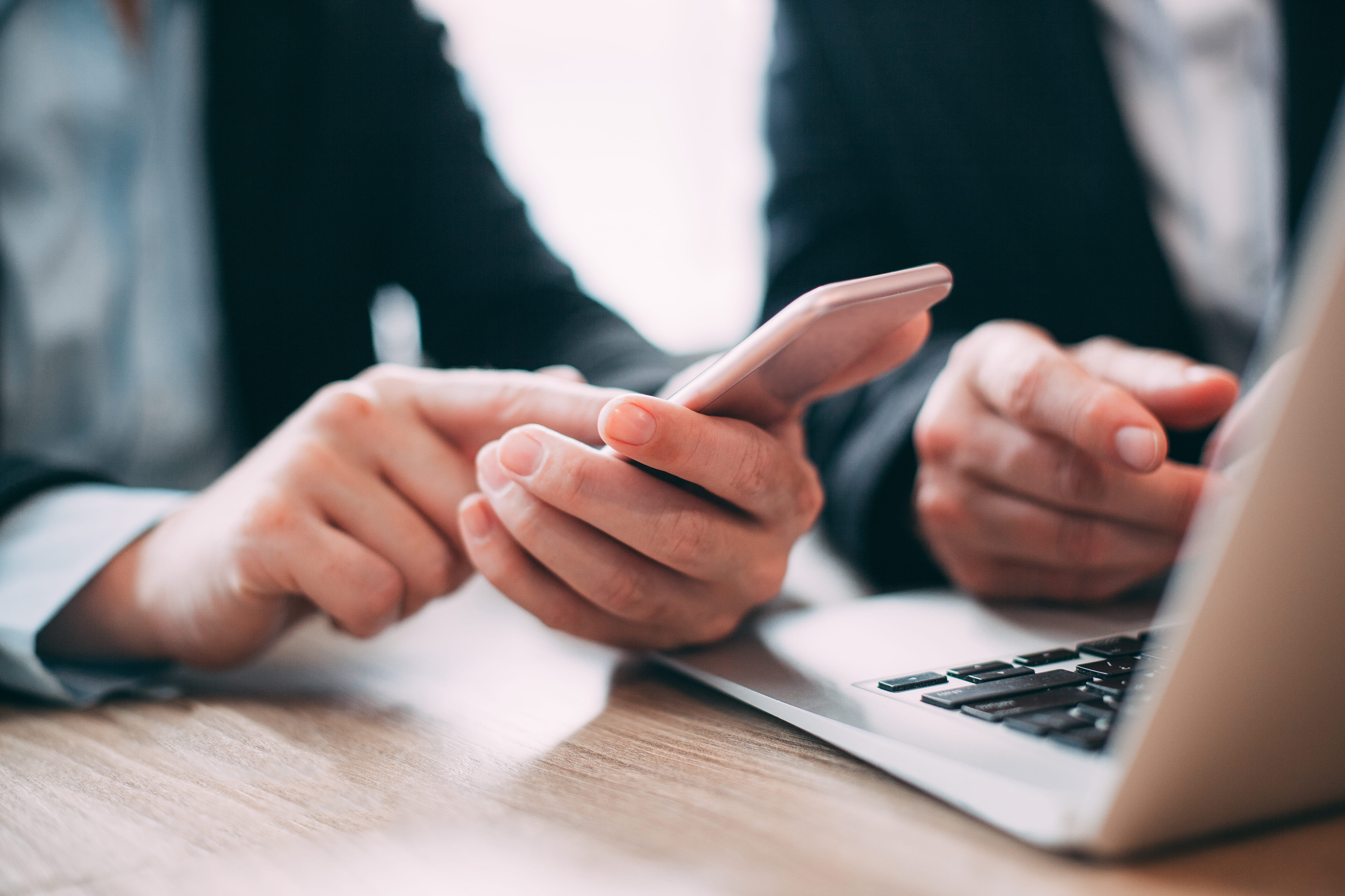 A laptop and hands taking notes at a table in office
