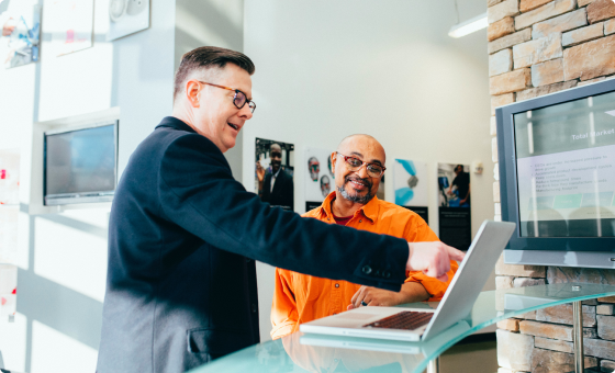 A man showing to a worker a dashboard on a computer screen