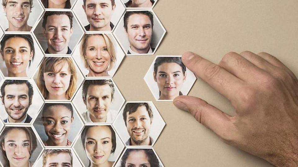 A puzzle is being composed, with the faces of the employees printed on the various pieces